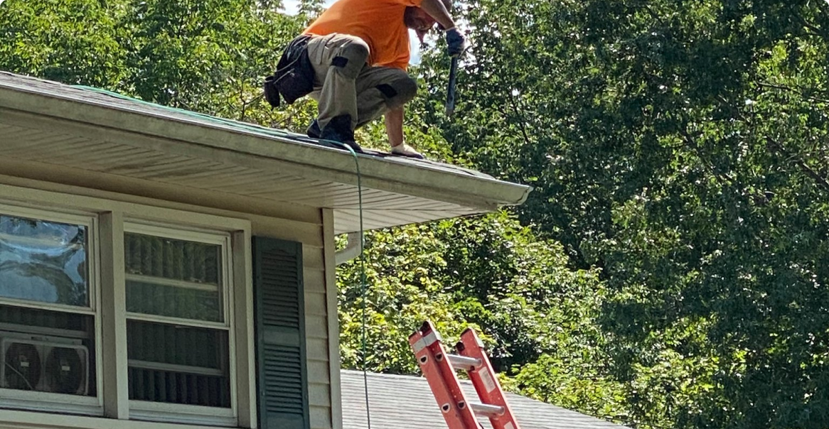 a man standing on top of a roof next to a ladder.