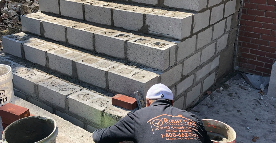 a man laying bricks on the side of a building.